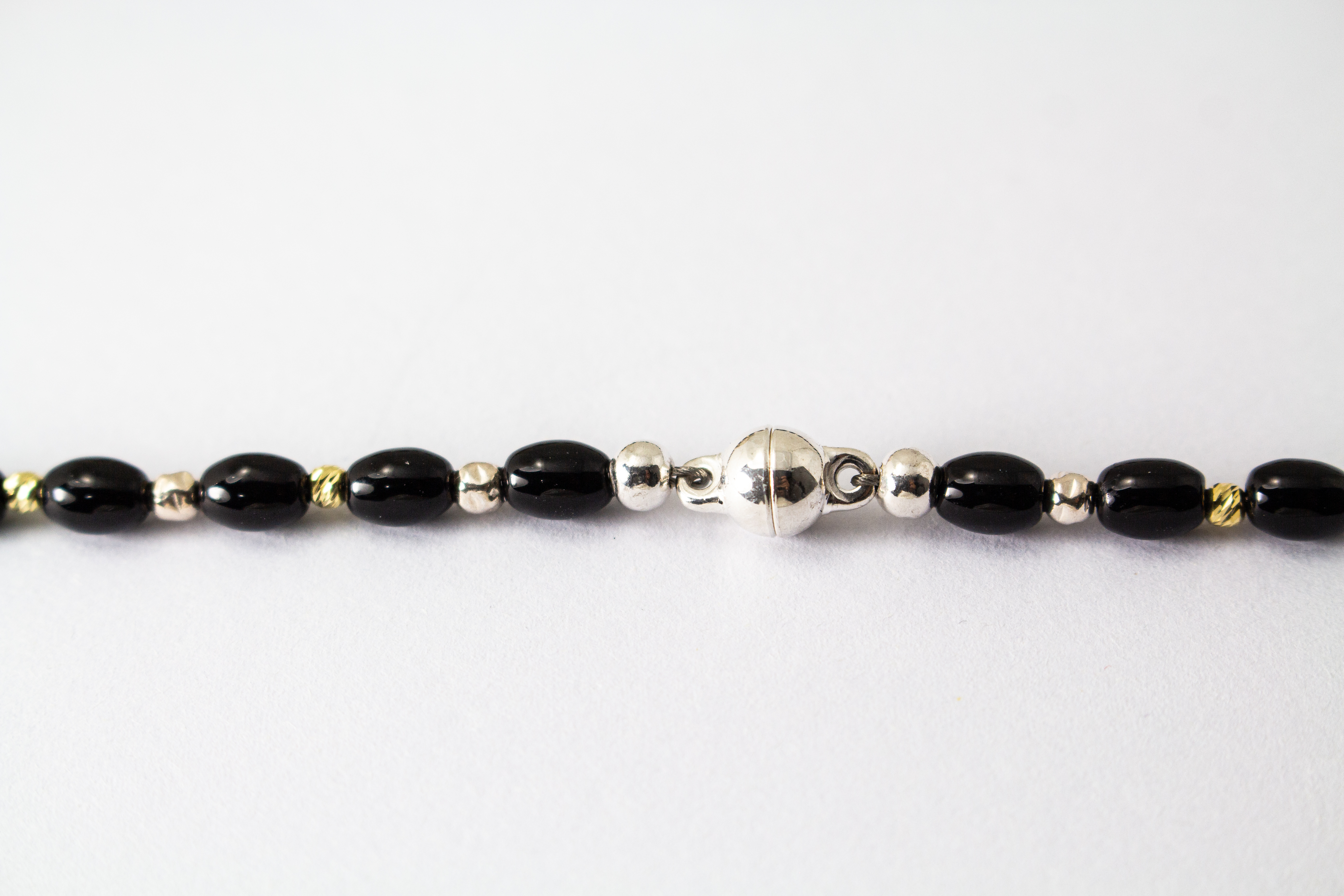Elegante Onyx Kette „Mitternachtsglanz“ mit schwarzen Onyx-Perlen, Zwischenteilen aus 925er Sterlingsilber und vergoldeten Silberdetails.