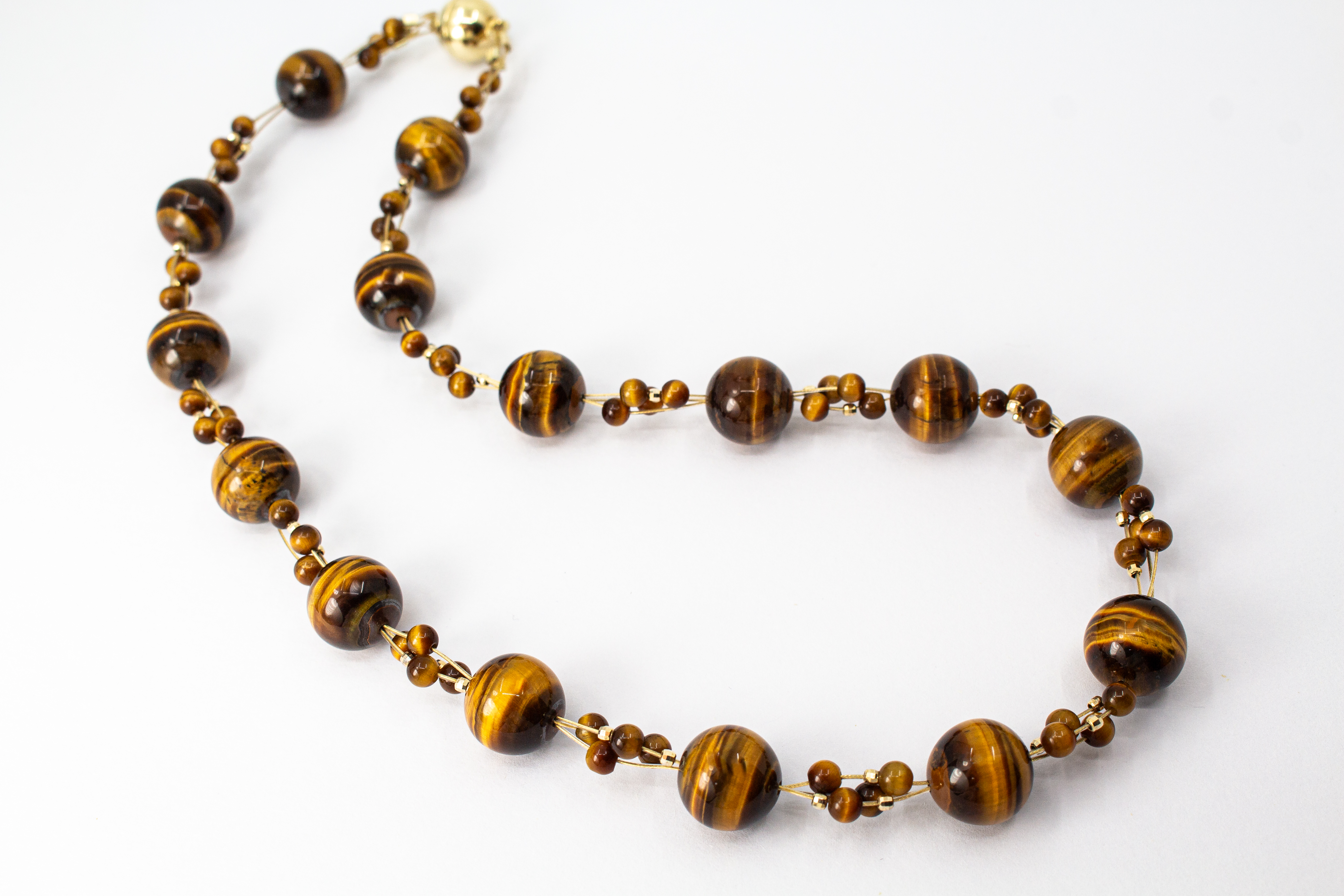 Eine handgefertigte Edelsteinkette der Goldschmiede Regina Kraus aus runden, braungoldenen Tigerauge-Perlen