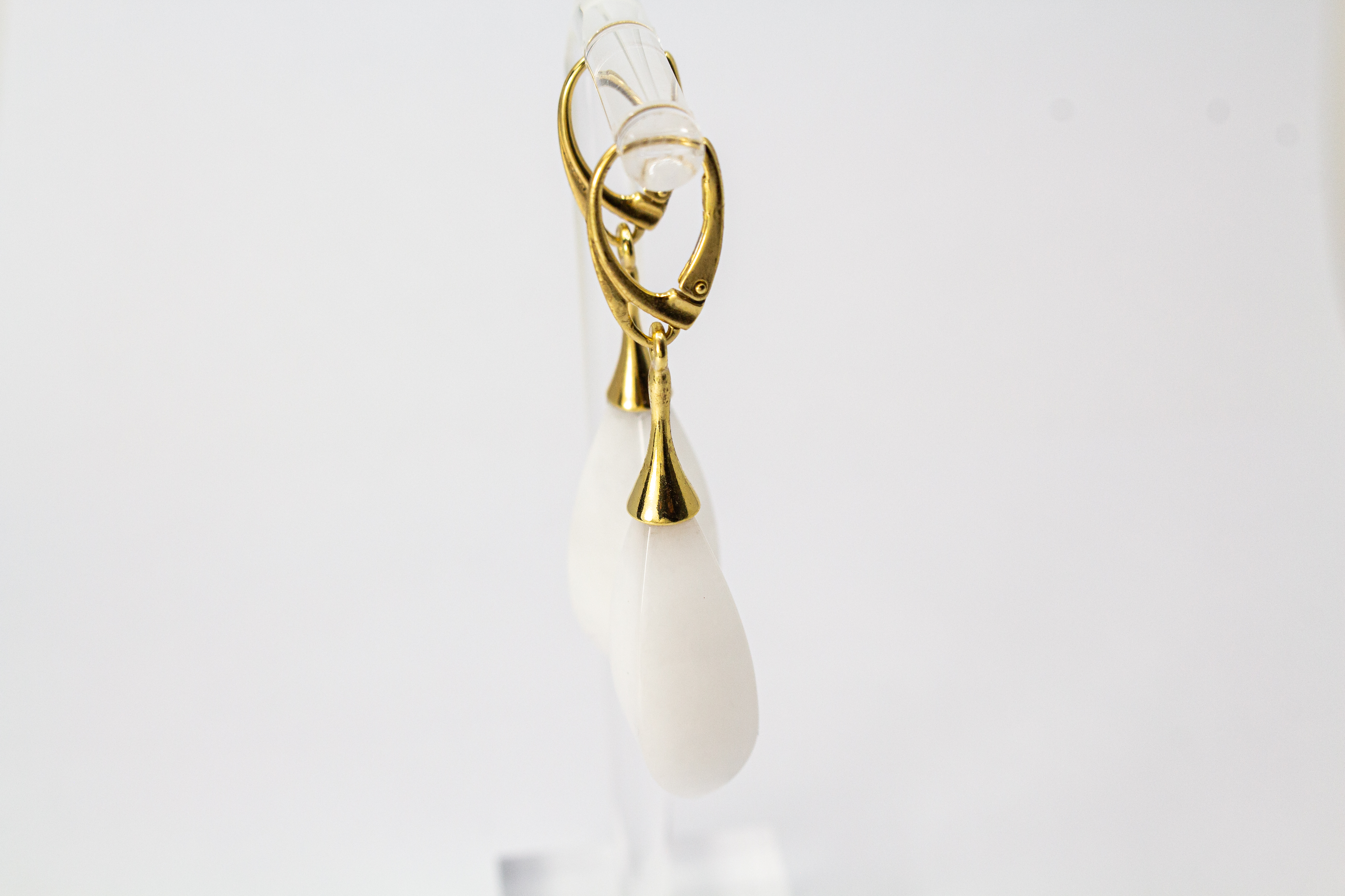 Elegante Tropfen-Ohrhänger mit weißem, porzellanartigen Kascholong-Edelstein und einer vergoldeten Brisur aus 925er Sterlingsilber von der Goldschmiede Regina Kraus.