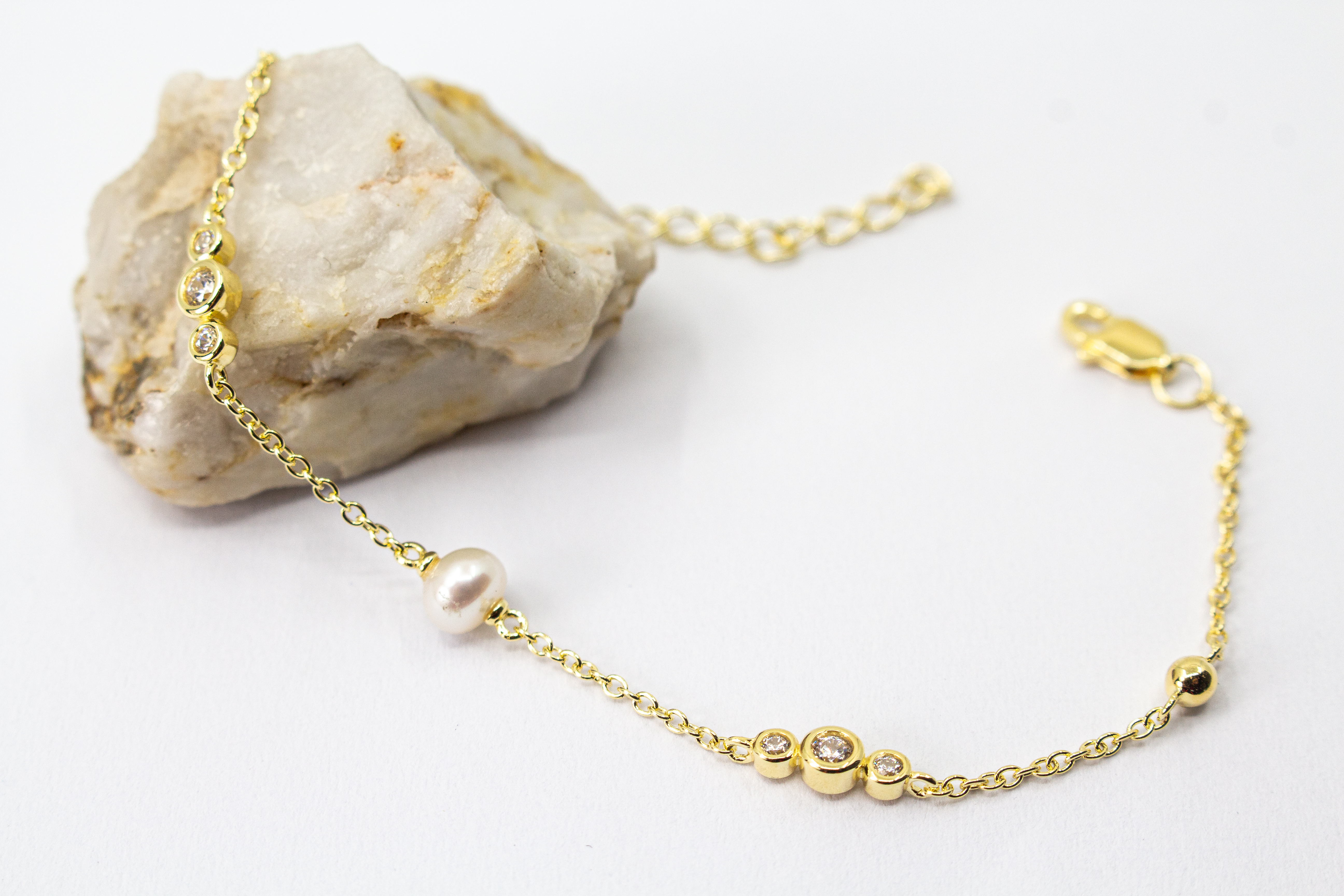 Edles Armband der Goldschmiede Regina Kraus aus vergoldetem 925er Silber mit einer zentralen Süßwasserperle, flankiert von funkelnden Zirkonia-Elementen und kleinen Goldkugeln