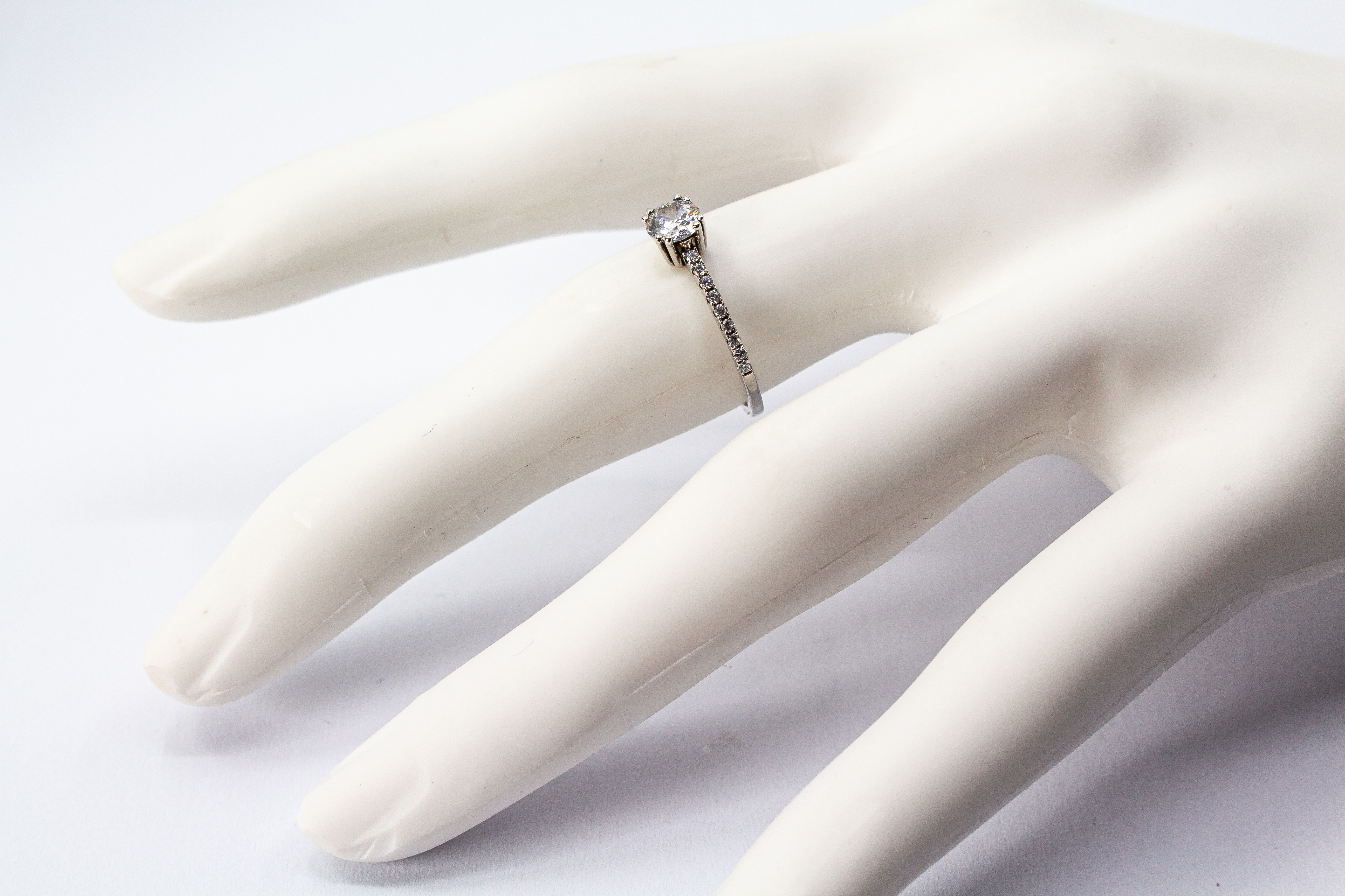 Eleganter Solitärring aus rhodiniertem 925er Silber mit einem großen, in einer Vierer-Krappenfassung gehaltenen Zirkonia und einer mit kleinen Zirkoniasteinen besetzten Ringschiene im Onlineshop von Goldschmiede Regina Kraus.