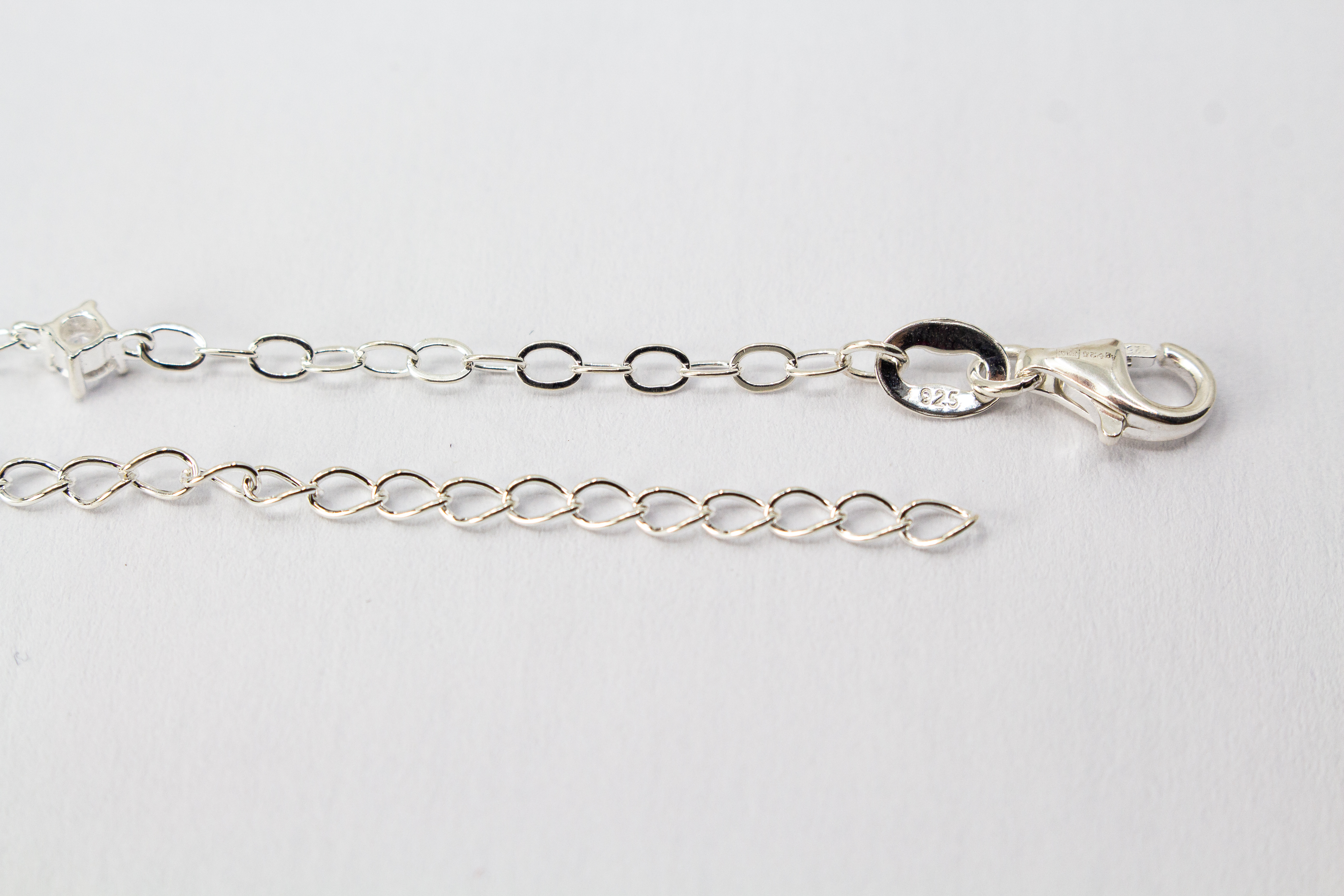 Filigranes Gliederarmband aus hochglanzpoliertem 925er Sterlingsilber mit einem flachen Stern-Anhänger und einem quadratisch gefassten Zirkonia-Kristall.
