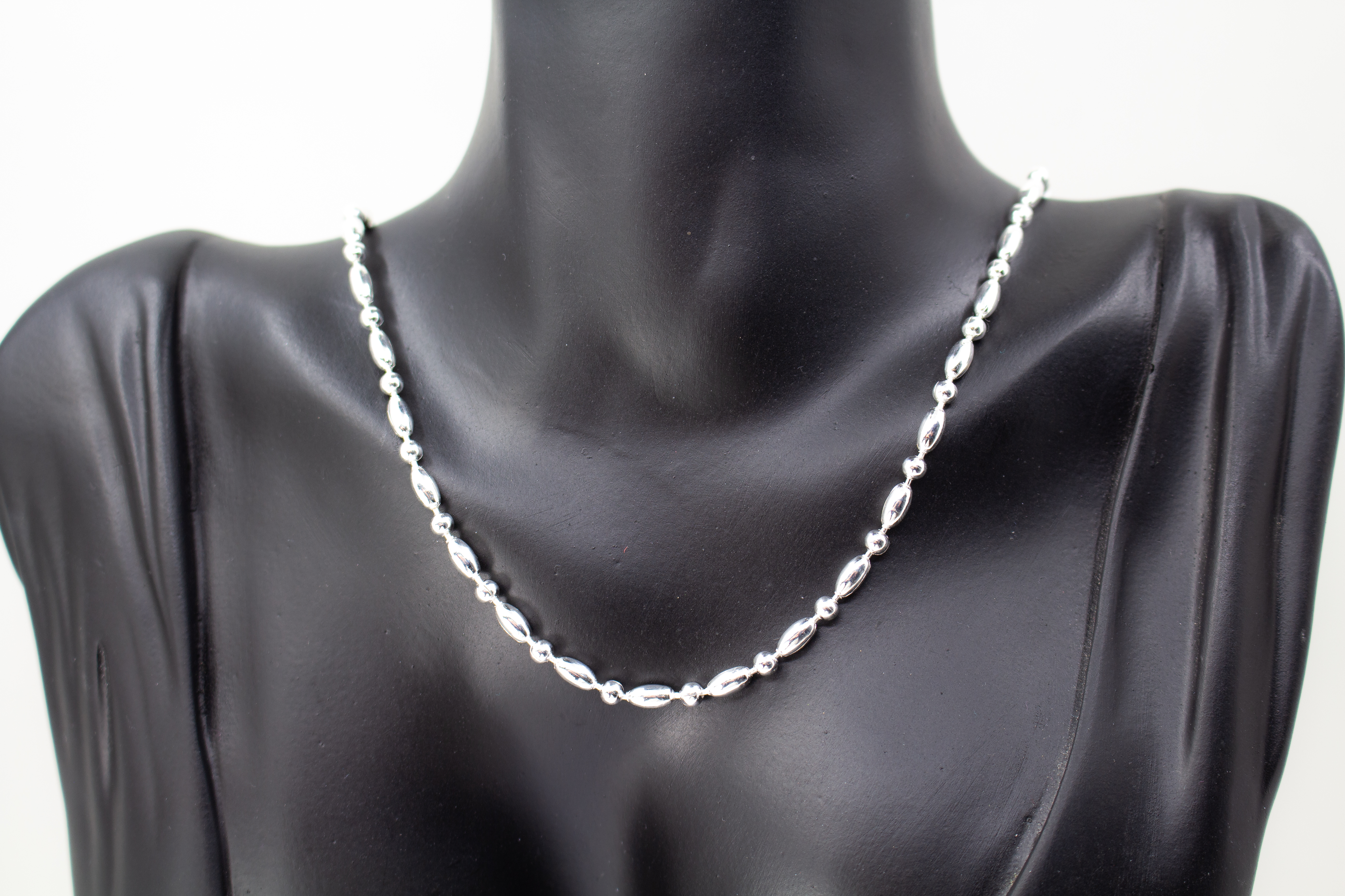 Filigrane Silberkette aus hochglanzpoliertem 925er Sterlingsilber mit einem rhythmischen Wechsel aus Oliven- und Kugel-Elementen auf hellem Untergrund, exklusiv erhältlich im Schmuck-Onlineshop der Goldschmiede Regina Kraus.