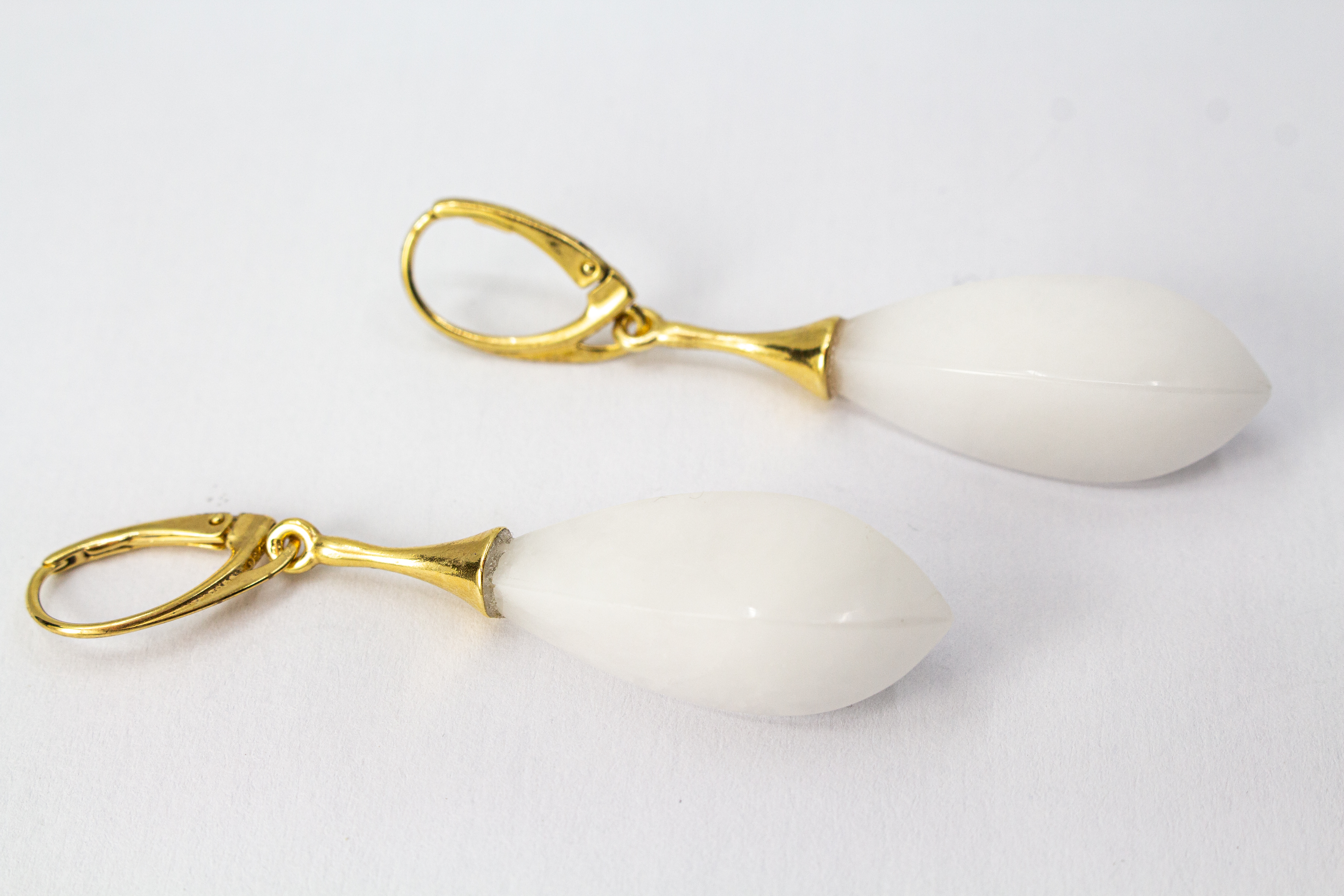 Elegante Tropfen-Ohrhänger mit weißem, porzellanartigen Kascholong-Edelstein und einer vergoldeten Brisur aus 925er Sterlingsilber von der Goldschmiede Regina Kraus.