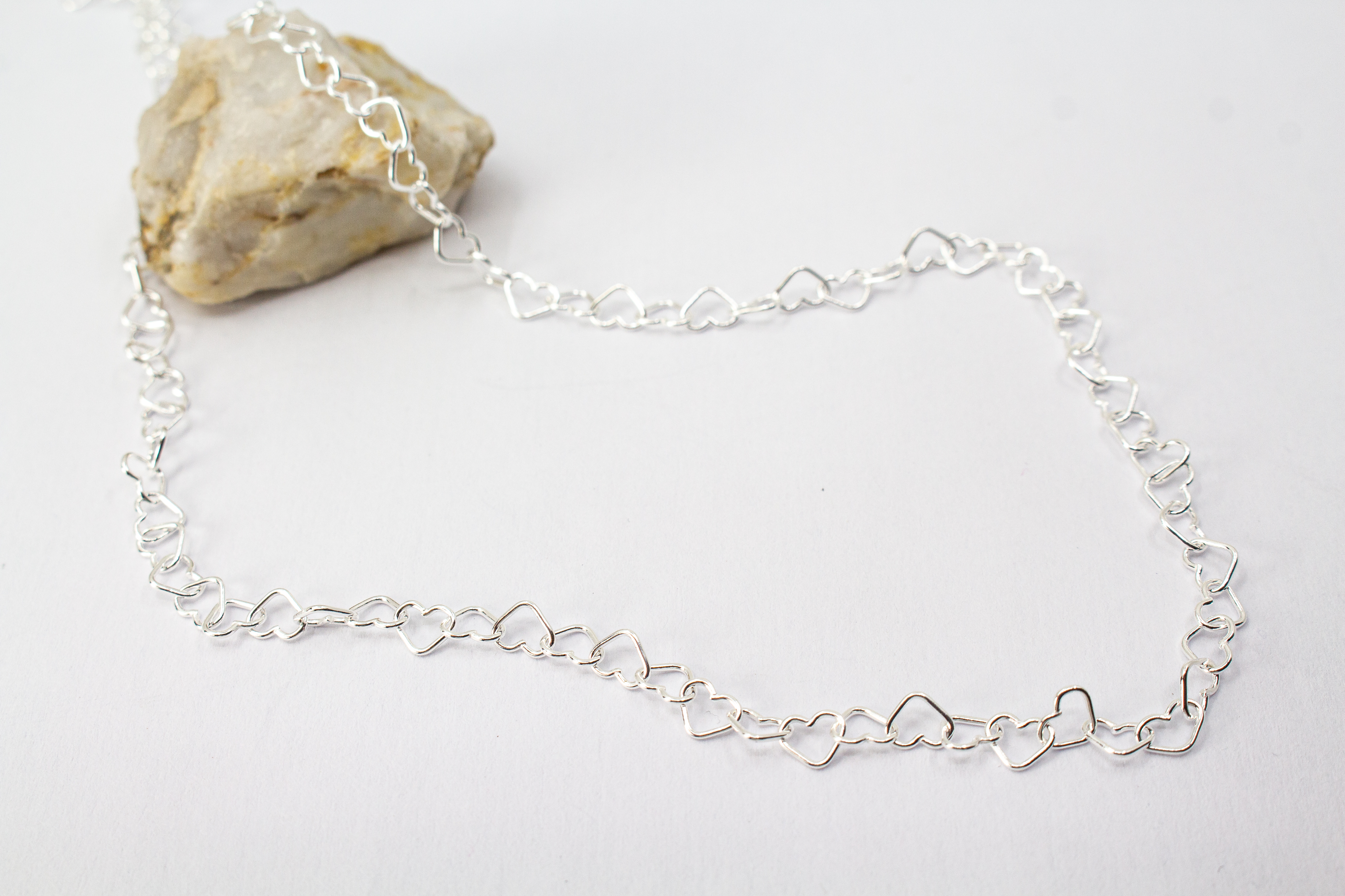 Zarte Halskette „Herz an Herz“ aus 925er Sterlingsilber, gefertigt aus einer Reihe kleiner, miteinander verbundener offener Herzen aus dem Onlineshop der Goldschmiede Regina Kraus.