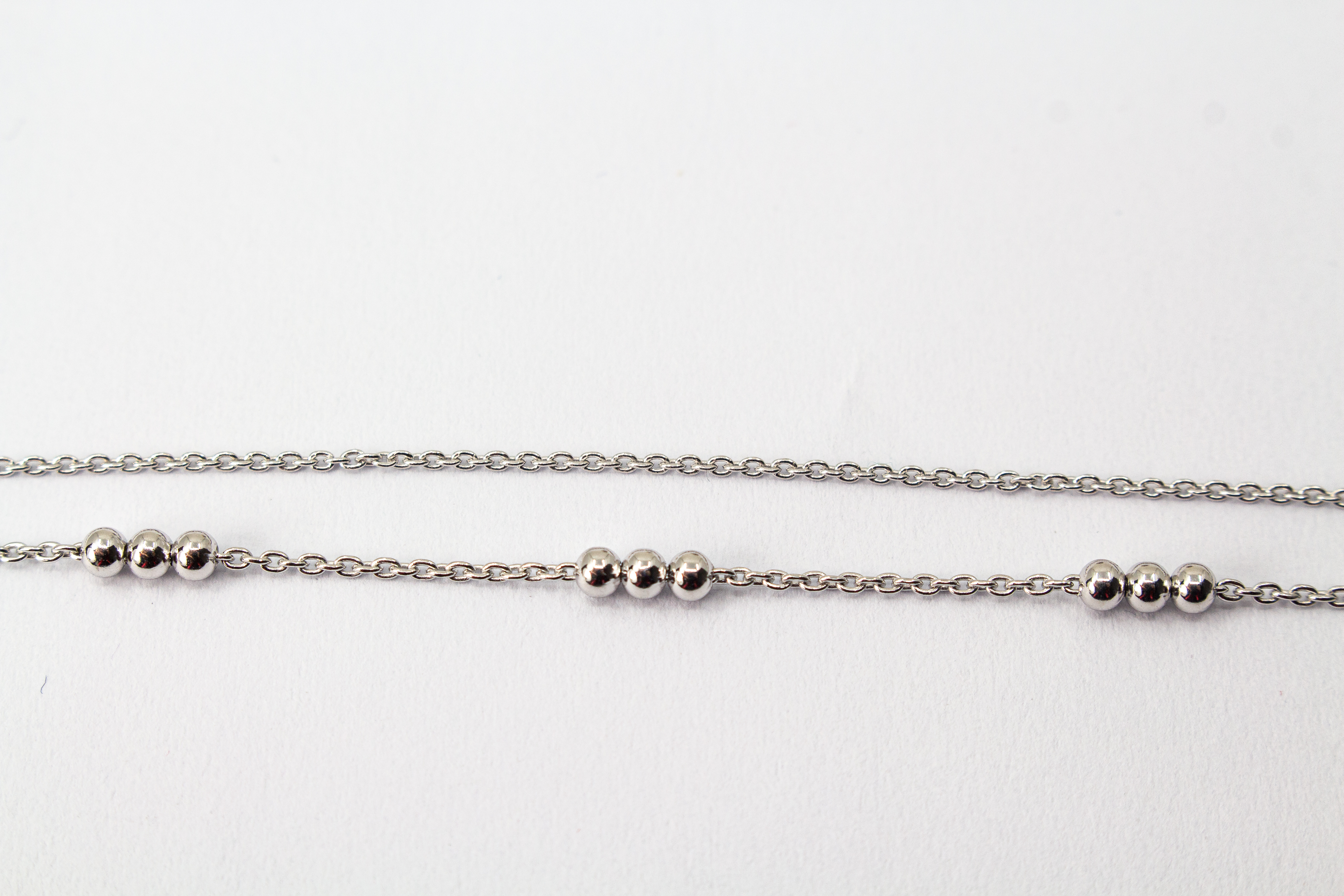 Zweireihiges Armband der Goldschmiede Regina Kraus aus hochwertigem rhodiniertem 925er Silber mit kleinen Silberkugeln in Dreiergruppen auf feinen Ankerketten.