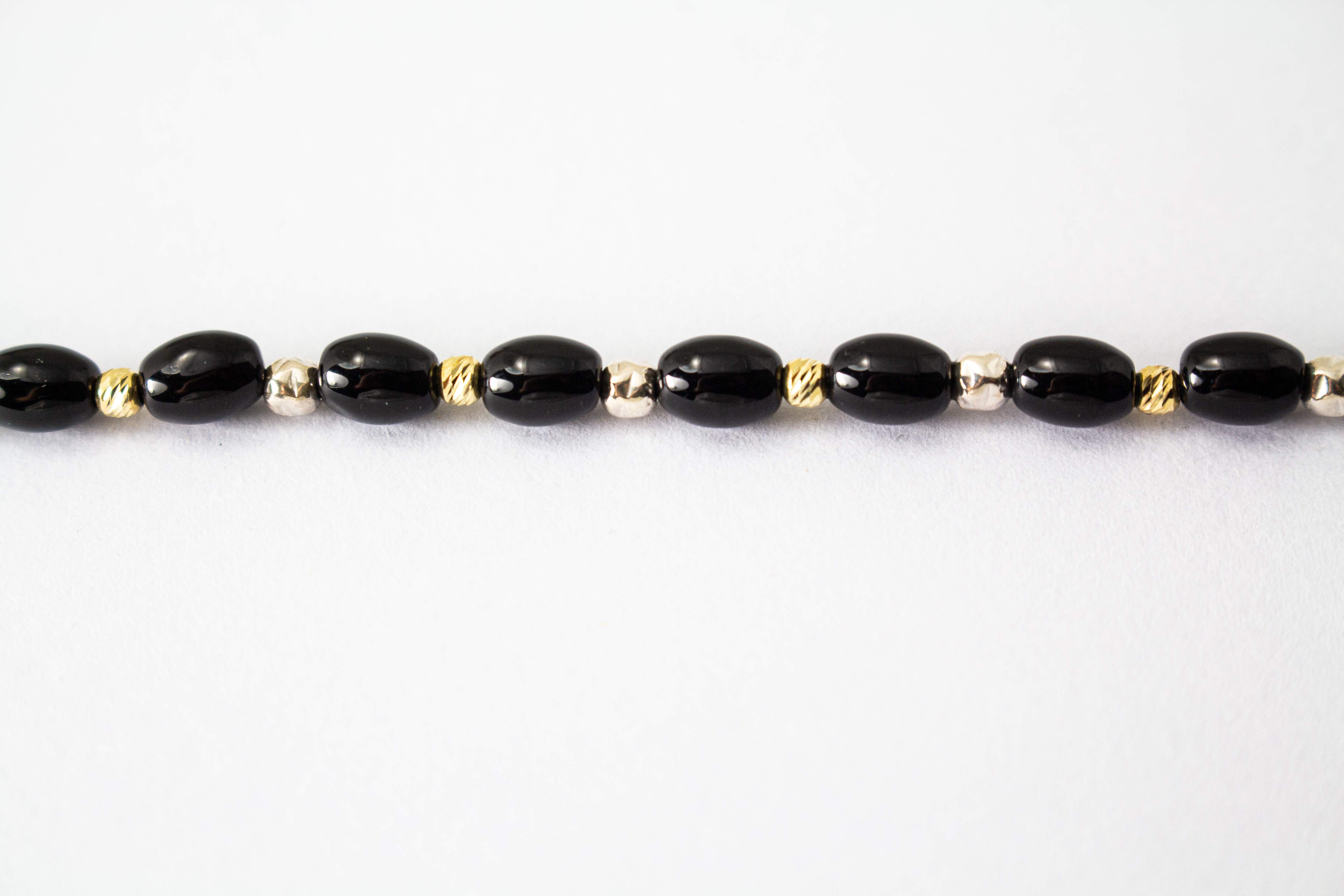 Elegante Onyx Kette „Mitternachtsglanz“ mit schwarzen Onyx-Perlen, Zwischenteilen aus 925er Sterlingsilber und vergoldeten Silberdetails.