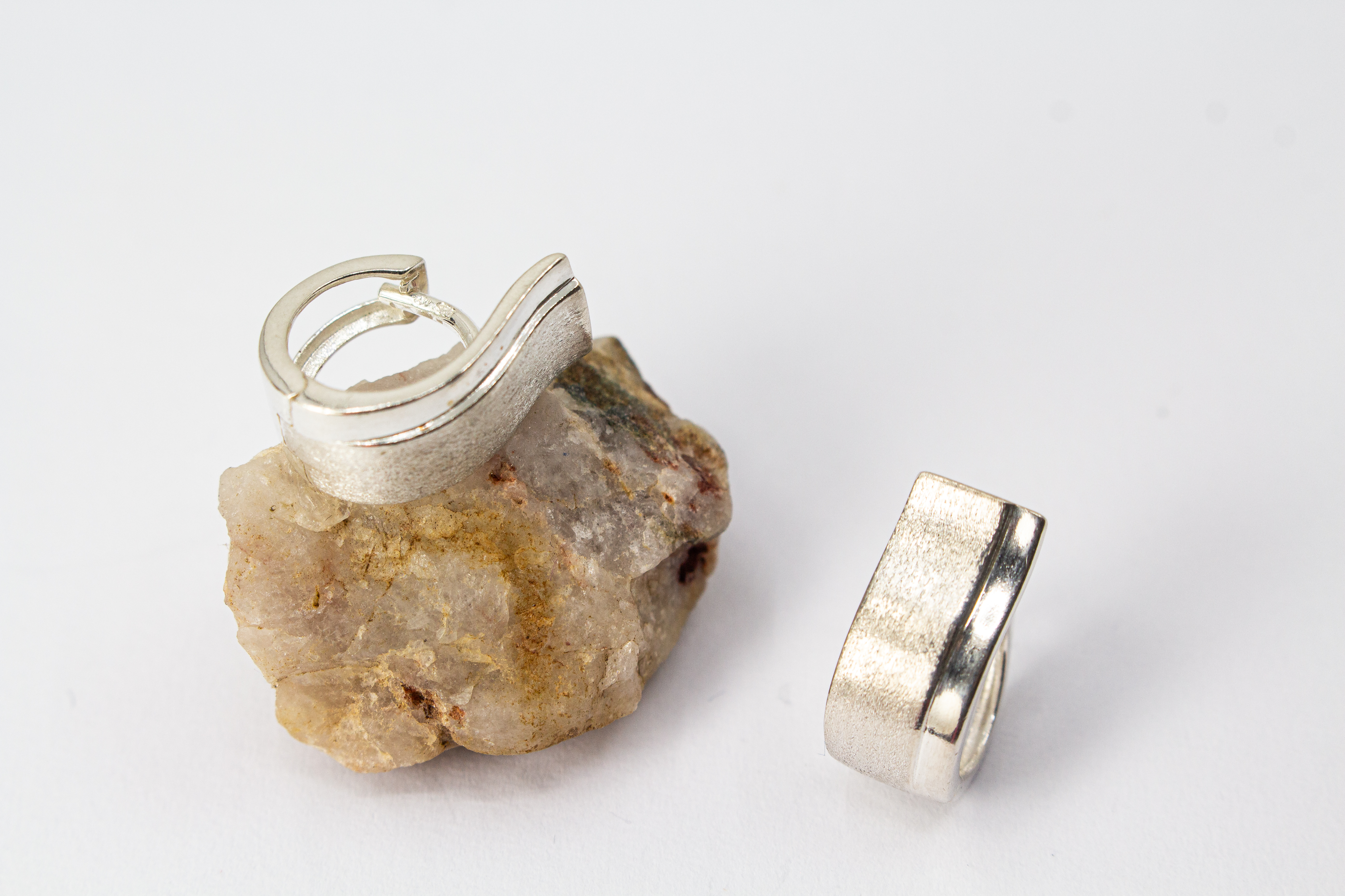 Breite Klappcreolen aus 925er Silber mit einer schwungvoll hochgezogenen, eismattierten Vorderseite und glänzend polierten Kanten im Onlineshop von Goldschmiede Regina Kraus.