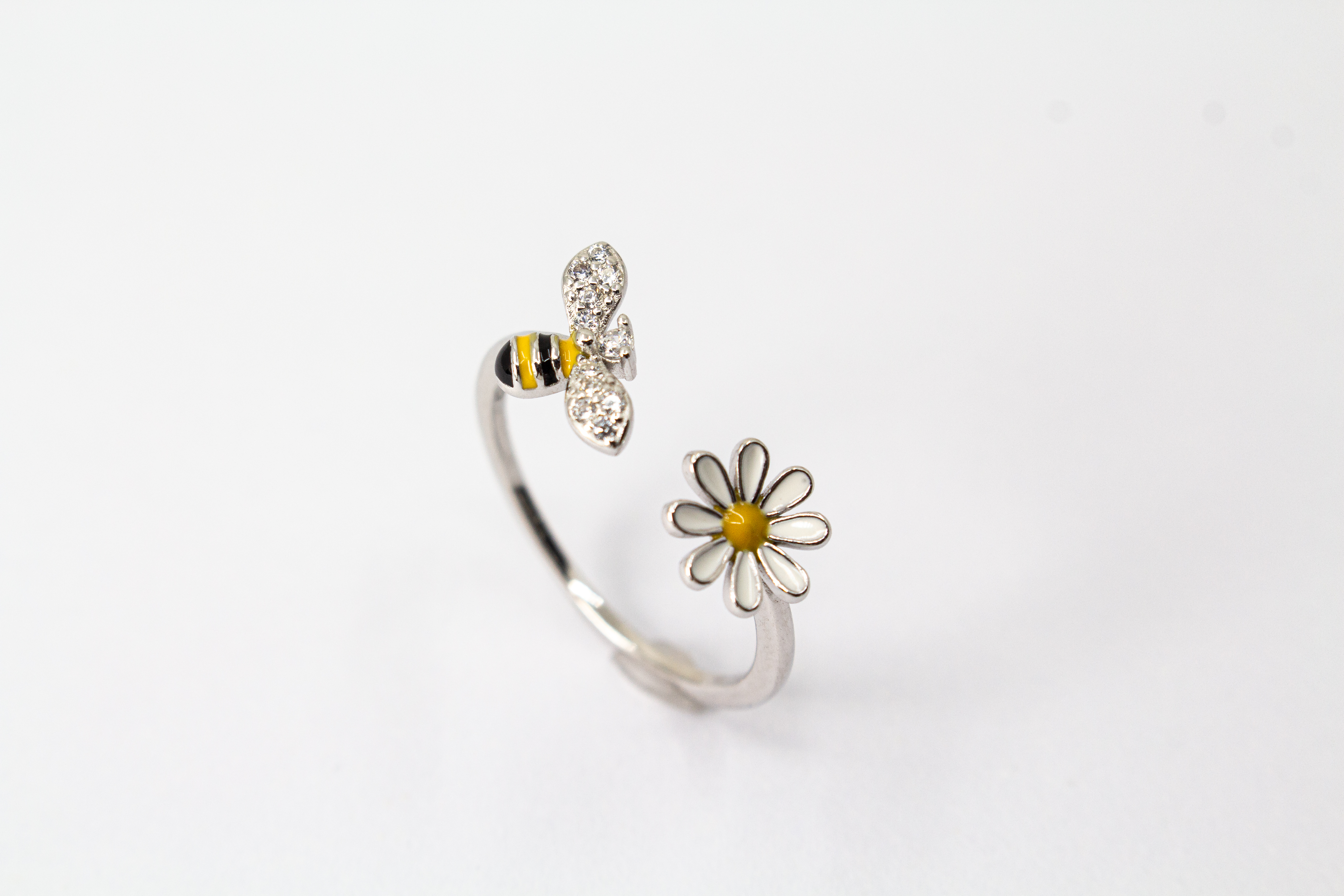 Offener Ring „Blütenbesuch“ aus rhodiniertem 925er Sterlingsilber mit Emaille-Blüte, funkelnder Biene und weißen Zirkonia.
