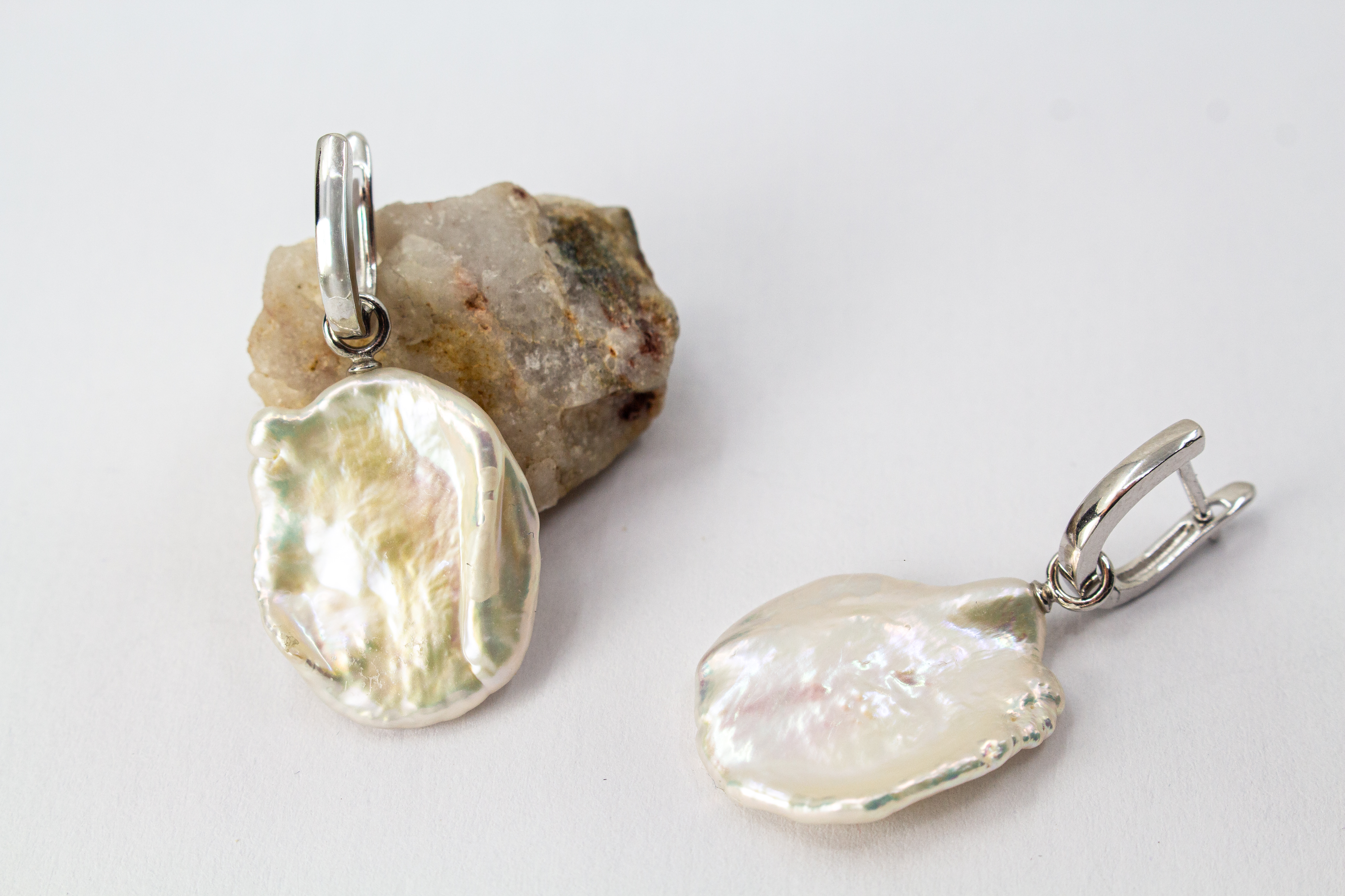 Ein Paar wandelbare Wechselcreolen „Meeresskulptur“ aus rhodiniertem 925er Sterlingsilber von der Goldschmiede Regina Kraus. Die Ohrringe tragen abnehmbare Anhänger aus großen, flachen weißen Keshi-Zuchtperlen, die durch ihre organische Freiform wie eine