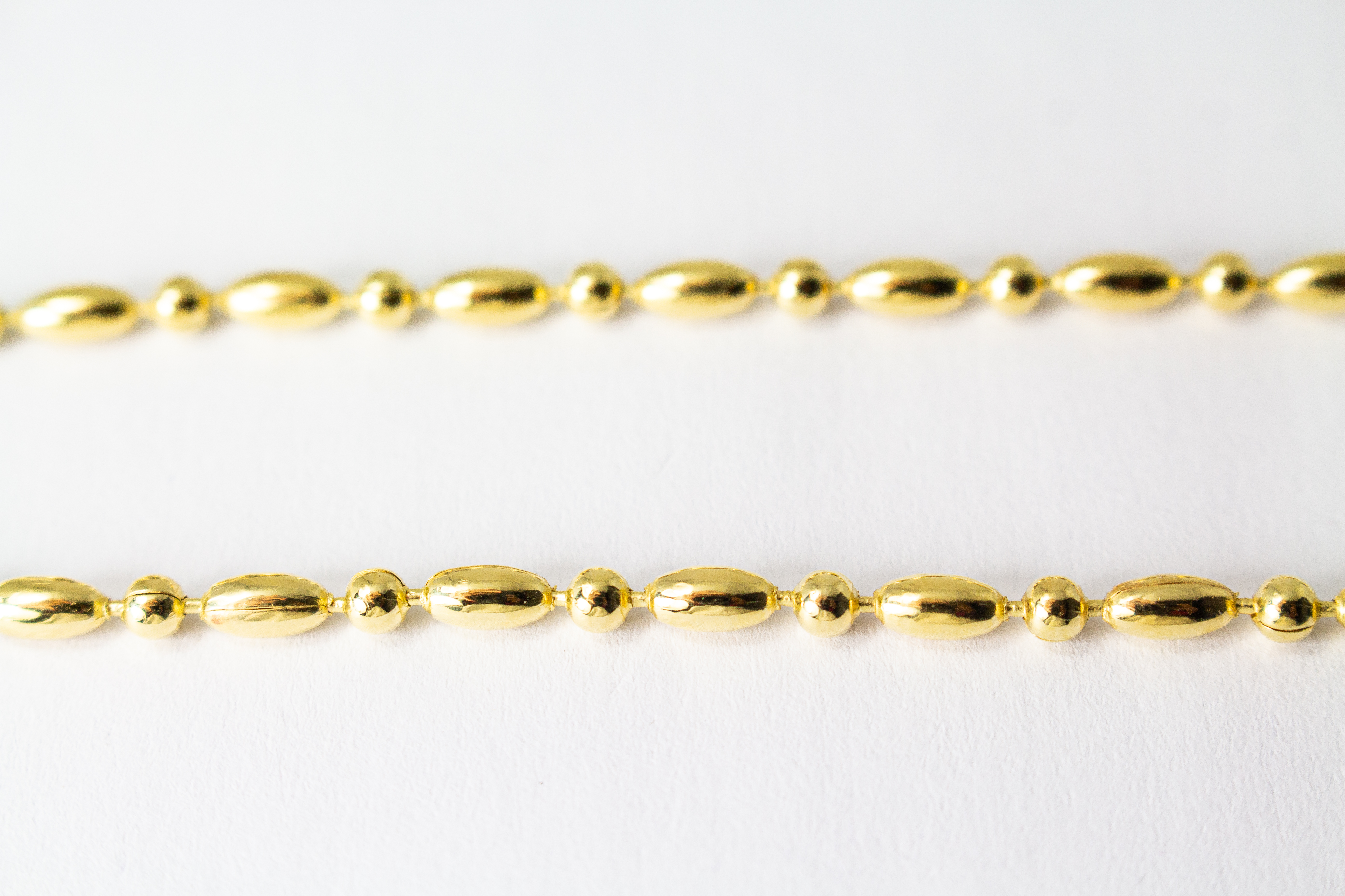 Filigranes, hochwertig vergoldetes Silberarmband (925er Silber, 20 Mikron Vergoldung) mit einem wechselnden Muster aus glänzenden Oliven- und Kugel-Elementen sowie Karabinerverschluss, erhältlich im Onlineshop der Goldschmiede Regina Kraus.