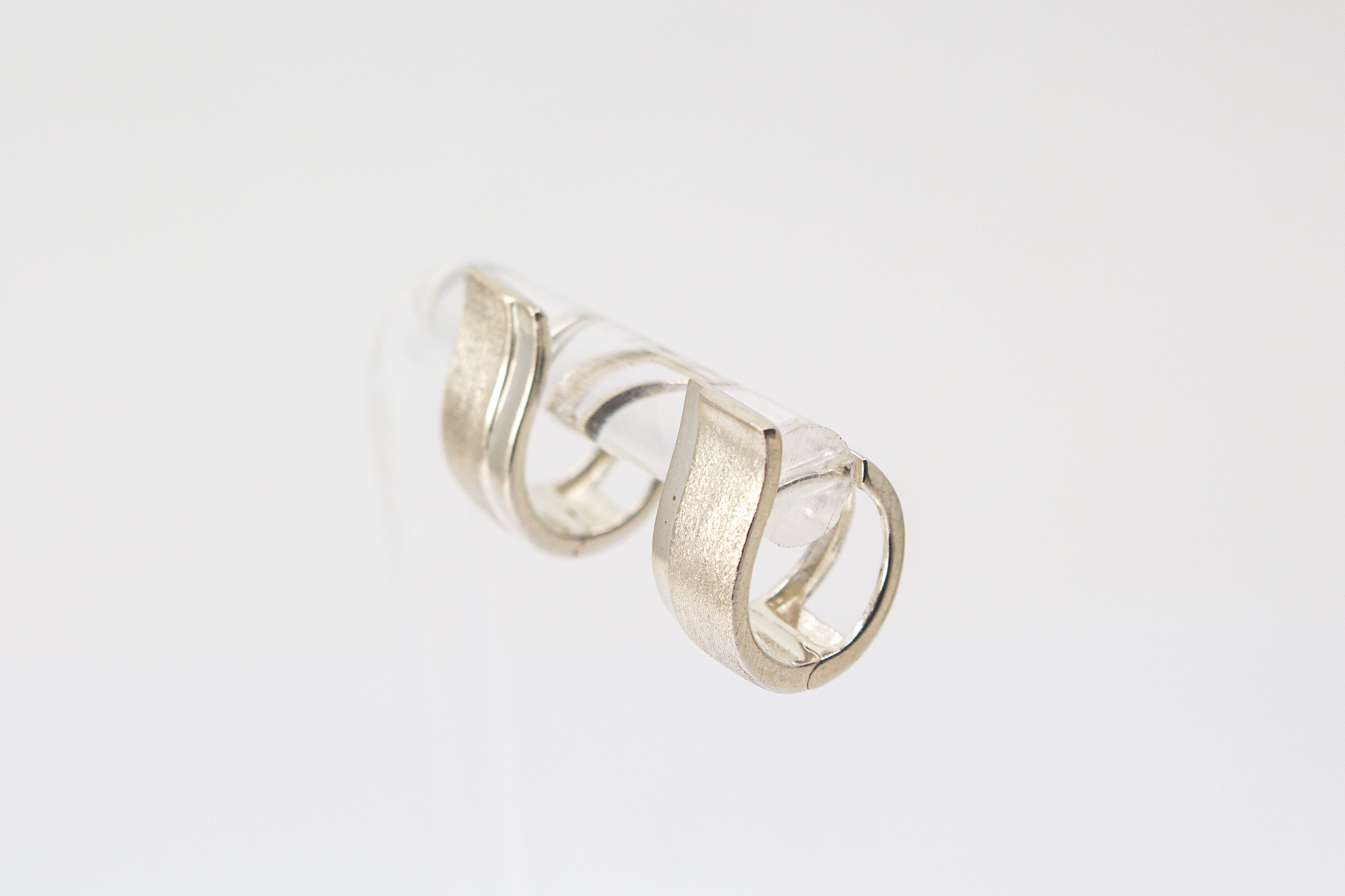 Breite Klappcreolen aus 925er Silber mit einer schwungvoll hochgezogenen, eismattierten Vorderseite und glänzend polierten Kanten im Onlineshop von Goldschmiede Regina Kraus.